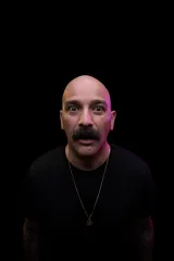 Tamer Kattan looking into the camera under magenta stage light